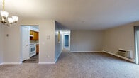 Located at 37 Sharon Rd in Waterbury, CT, this single-floor, two-bedroom, one-bathroom residence offers a comfortable and functional layout. The living room is a bright, open space featuring plush carpeting, neutral-toned walls, and a sliding glass door that opens to a private balcony. The balcony overlooks lush greenery and mature trees, providing a serene outdoor view. A wall-mounted HVAC unit and baseboard heating ensure year-round comfort. A pass-through window connects the living area to the kitchen, which features warm wood cabinetry, creating an open and connected feel between spaces.

The primary bedroom is generously sized, bathed in natural light from two windows with blinds, and equipped with both a wall HVAC unit and baseboard heating. The second bedroom also features carpeted flooring, a window with natural light, and baseboard heating. A dedicated closet provides built-in shelving for organized storage. The full bathroom includes a single-sink vanity with wood cabinetry, a tub-shower combination with classic tile surround, and wood-style flooring. The overall ambiance is clean, neutral, and move-in ready, with greenery views accessible from multiple rooms.