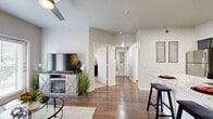 This thoughtfully designed single-floor residence offers three bedrooms and three full bathrooms within a efficiently organized layout. The open living area serves as the heart of the home, featuring warm wood-style flooring, a ceiling fan, and large French doors that invite natural light and outdoor views. A built-in fireplace console anchors the living space, adding both style and functionality.

The galley-style kitchen is outfitted with granite countertops, slate-gray shaker cabinetry, a decorative arabesque tile backsplash, and a full suite of stainless steel appliances. A breakfast bar provides casual seating and connects the kitchen to the main living area.

Each bedroom is carpeted and receives natural light through large windows dressed with blinds and curtains. The primary bedroom offers a comfortable, well-proportioned layout. A dedicated walk-in closet features multi-tier wire shelving, maximizing storage capacity.

All three bathrooms maintain a consistent, modern aesthetic with granite-topped gray vanities, large framed mirrors, and tub-shower combinations finished with white tile surrounds and wood-style flooring. A central hallway connects the bedrooms and bathrooms, keeping the layout organized and easy to navigate. Neutral gray-toned walls throughout create a cohesive and contemporary ambiance.