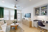 Located at 17011 W Little York Rd in Houston, TX, this thoughtfully designed one-bedroom, one-bathroom residence makes efficient use of its space across a single floor. The open-concept living, dining, and kitchen area serves as the heart of the home, bathed in natural light through large windows dressed with rich green curtains and wood-slat blinds. Ceiling fans with integrated lighting enhance comfort throughout. The living area features light hardwood-style flooring and a built-in nook with open shelving and a dark granite desk surface, perfect for a home office setup. The kitchen is outfitted with soft gray cabinetry, dark granite countertops, a white tile backsplash, stainless steel appliances, and a breakfast bar with pendant lighting — ideal for casual dining. A dedicated pantry and in-unit laundry add everyday convenience. The bedroom is a serene retreat with natural light, hardwood-style flooring, and direct access to the bathroom. The bathroom features a dark granite vanity, gray cabinetry, and a tub-shower combination. Additional highlights include a closet, a patio for outdoor enjoyment, and crown molding throughout the main living areas, lending a polished, cohesive aesthetic to the entire space.