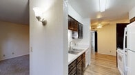 Located at 6932 Pamlico Dr in El Paso, TX, this single-floor, 2-bedroom, 1-bathroom home delivers a straightforward and functional layout well-suited for comfortable everyday living. The kitchen features rich dark wood cabinetry with arched glass-panel doors, a double-basin stainless steel sink, light countertops, and a built-in dishwasher. A wall sconce adds a warm accent near the entryway, while light wood-look flooring runs through the kitchen and connecting hallway, creating a clean, cohesive look. The living area transitions to carpet underfoot and opens to the rest of the home through a textured-ceiling space equipped with ceiling fans for climate comfort. The generously sized primary bedroom is carpeted and bathed in natural light from a window dressed with sheer curtains. It features a ceiling fan and a sliding-door closet with built-in shelving for organized storage. The second bedroom is similarly carpeted, bright, and airy, also featuring a ceiling fan and a window with natural light. The bathroom is clean and functional, with light wood-look flooring, a full-size soaking tub with shower, a toilet, and a vanity with dark wood cabinetry. Throughout the home, neutral wall tones and textured ceilings create a calm, understated ambiance.