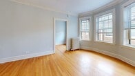 Located at 1002 1/2 North Boulevard in the historic village of Oak Park, Illinois, this compact single-floor unit offers a well-organized layout comprising a living room, kitchen, bathroom, and two hallways. Throughout the space, warm hardwood flooring adds a timeless character that ties each room together cohesively.

The living room is a standout feature, showcasing a graceful bay window arrangement that allows generous natural light to fill the room. Soft blue-gray walls, crisp crown molding, and a classic cast-iron radiator lend the space a charming, period-appropriate aesthetic. A closet with shelving is accessible directly from the living area, adding practical storage.

The galley-style kitchen is efficiently designed, featuring rich wood cabinetry, a dark tile backsplash, and a full suite of stainless steel appliances including a gas range, refrigerator, and over-the-range microwave. A window at the end of the kitchen brings in additional natural light.

The bathroom is finished with neutral floor-to-ceiling tile, a white vanity, and a full soaking tub with a shower. Two windows keep the space bright and ventilated. Hallways connecting the rooms provide smooth circulation throughout. Overall, the unit presents a clean, classic ambiance rooted in Oak Park's architectural heritage.