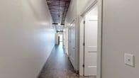 This thoughtfully designed one-bedroom, one-bathroom unit at 600 N Franklin St in Syracuse, NY, blends industrial character with contemporary updates across a generous single-floor layout. The space retains striking original elements, including reclaimed wood plank ceilings with exposed beams, ductwork, and industrial pendant lighting that run throughout, lending the unit a distinctive loft-like aesthetic.

The open living area features polished concrete-style flooring, exposed structural columns, and access to a brick-accented wall with a window that draws in natural light. The kitchen is outfitted with white shaker cabinetry, a mosaic tile backsplash, stainless steel appliances including a refrigerator, range, microwave, and dishwasher, and is seamlessly integrated into the main living space.

A long hallway connects the private areas of the unit, lined with panel doors and illuminated by pendant fixtures beneath the reclaimed wood ceiling. The bathroom features large-format tile flooring, a white vanity with ample drawer storage, and subway tile wall accents. Two closets provide generous storage, including a walk-in closet equipped with wire shelving. A dedicated utility room and a well-proportioned bedroom complete the layout.