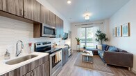 This one-bedroom apartment in Champaign, IL, maximizes its 420 square feet with a thoughtful layout and contemporary design. The space features a single floor plan with a generous 140 square foot primary bedroom. The living area is open and bright, with large windows allowing natural light to flood the space. Sheer curtains provide privacy while maintaining an airy feel.

The kitchen boasts modern wood-grain cabinetry, stainless steel appliances, and a sleek subway tile backsplash. The living room accommodates a comfortable sectional sofa and is adorned with minimalist artwork and lush plants, creating a cozy yet stylish atmosphere.

The bedroom continues the modern aesthetic with a large bed, ample storage, and artistic decor. A full-length mirror and strategic lighting enhance the sense of space. The bathroom features a contemporary vanity with under-sink storage and a well-lit mirror.

Throughout the apartment, warm wood-tone flooring unifies the space, while a neutral color palette with pops of blue in the furnishings adds visual interest. Practical amenities include in-unit laundry facilities, adding convenience to this compact yet well-appointed urban dwelling.