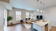 Located at 7920 Cameron Ln in Montgomery, Ohio, this well-designed 2-bedroom, 1-bathroom residence offers a thoughtfully arranged single-floor layout that maximizes comfort and functionality. The open-concept living and kitchen area serves as the heart of the home, featuring warm wood-look flooring, neutral toned walls, and large windows that invite abundant natural light. The kitchen is outfitted with white shaker cabinetry, quartz countertops, a center island with seating, stainless steel appliances, and stylish pendant lighting overhead. The living area flows seamlessly from the kitchen and provides direct access to a private balcony, extending the living space outdoors. The primary bedroom offers plush carpeting, generous natural light through dual windows with outdoor views, and comfortable proportions. The second bedroom is equally well-appointed with soft carpeting and a bright window. The full bathroom features a quartz-topped vanity with white cabinetry, wood-look flooring, and a full tub-shower combination. A dedicated closet adds to the home's practical storage solutions. Clean lines, modern finishes, and a cohesive neutral palette throughout create a bright, contemporary ambiance well-suited to everyday living.