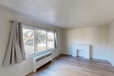 Located in Edmonton's established neighbourhood, this one-bedroom, one-bathroom unit offers a thoughtfully organized single-floor layout. The living room is bright and welcoming, featuring large windows that frame views of mature trees outside, light hardwood-style flooring throughout, a textured ceiling, and a charming decorative white fireplace mantle that serves as a focal point. Radiant baseboard heaters provide reliable warmth throughout the space.

The combined dining and kitchen area is efficiently designed, featuring white cabinetry with ample upper and lower storage, open shelving, dark countertops, a tile backsplash, and a stainless steel sink. A white electric range completes the functional cooking space.

The bedroom is a comfortable size, filled with natural light from a large window overlooking greenery, and includes a double sliding-door closet along with access to additional closet storage. In total, the unit offers four closets, providing generous storage options throughout.

The bathroom features a full tub and shower combination with floor-to-ceiling tile surround in a warm neutral tone. A connecting hallway ties the rooms together, keeping the layout practical and well-organized. Light hardwood-style flooring flows consistently throughout, reinforcing a clean and cohesive aesthetic.