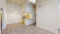 Located at 12138 Holbrook Dr in Hudson, FL, this single-story, 2-bedroom, 2-bathroom home offers a well-organized layout with a welcoming entrance leading into a bright, open-concept living, dining, and kitchen area. The living space stands out with notably high vaulted ceilings, a ceiling fan with light fixture, a decorative pendant light, and neutral carpet flooring that extends throughout, creating a spacious and airy atmosphere.

The kitchen is designed as a galley-style space featuring light wood flooring, white cabinetry with wood trim accents, light-toned countertops, a stainless steel sink, a white electric range, and a refrigerator. A pass-through counter connects the kitchen to the dining and living areas, enhancing the open feel. An adjacent pantry provides additional storage.

The primary bedroom is generously sized with multiple windows offering pleasant outdoor views and abundant natural light, while the second bedroom also features carpet, a window, and a closet. Both rooms benefit from textured ceilings and ceiling ventilation.

The two bathrooms are clean and functional; one includes a tub/shower combination, while the other features a walk-in shower. Both have light wood flooring, a single vanity with light countertop, and a mirror. A dedicated laundry area and multiple closets throughout add practical convenience to this efficiently designed home.
