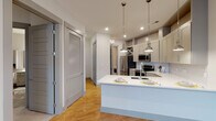 Located at 900 Hobbs Rd in Greensboro, NC, this single-floor residence offers a thoughtfully designed layout with modern finishes throughout. The open-concept kitchen is a standout feature, showcasing gray shaker-style cabinetry that extends to the ceiling, white quartz countertops, a subway tile backsplash, and stainless steel appliances including a refrigerator, range, and over-the-range microwave. A peninsula with an undermount sink and pendant lighting serves as a natural gathering point and provides additional prep and dining space. Warm hardwood-style flooring flows through the main living areas, complemented by neutral walls and recessed lighting that enhance the bright, airy feel. The living area is spacious and open, featuring a ceiling fan and glass French doors that allow natural light and provide access to an outdoor balcony. The bedroom is carpeted for comfort and includes a window with exterior views and ample wall space. The bathroom is well-appointed with a tiled tub-and-shower combination, gray vanity cabinetry, a white quartz countertop, and a wall-mounted storage cabinet. A dedicated in-unit laundry area with a full-size washer and dryer and overhead wire shelving adds practical convenience. Louvered closet doors throughout provide ample storage options.