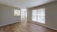 Located at 4803 New Hope Rd in Raleigh, NC, this single-floor home offers a functional and comfortable layout with a clean, neutral aesthetic throughout. The living area is a welcoming, open space finished with warm wood-look flooring and large windows fitted with blinds that invite ample natural light while maintaining privacy. A charming pass-through window connects the living area to the kitchen, which features white cabinetry and additional windows that brighten the workspace. The kitchen flows into a dedicated dining area, creating a convenient and cohesive layout ideal for everyday living and entertaining. The bedrooms are carpeted for comfort and each is equipped with a ceiling fan with light fixture, providing both airflow and ambient lighting. The rooms offer generous wall space and windows that bring in natural light. The bathroom is finished with clean white tile surrounding a full soaking tub and shower combination, complemented by chrome fixtures for a crisp, timeless look. Throughout the home, neutral gray-toned walls and white trim create a bright, move-in ready environment. The consistent, understated design palette makes this home a versatile and practical space in the Raleigh area.