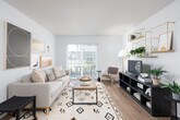 This single-floor residence is designed with a clean, contemporary aesthetic, combining functional layout with modern finishes throughout. The open-concept main living area seamlessly connects the kitchen, dining, and living spaces, all unified by warm-toned luxury vinyl plank flooring. The kitchen is outfitted with stainless steel appliances, rich walnut-toned cabinetry, a built-in range and microwave, and a central island featuring a white quartz countertop with an undermount sink — an ideal workspace and casual gathering point. Pendant lighting above the island adds a refined touch. Adjacent to the kitchen, the dining area comfortably accommodates a full table and chairs, with neutral walls providing a versatile backdrop. The living room benefits from abundant natural light, courtesy of a large sliding glass door that opens directly to a private patio, offering outdoor views of the surrounding community. Both bedrooms are well-proportioned with plush carpeting and ample natural light from large windows fitted with blinds. The full bathroom features a wide vanity with a white quartz countertop, a walnut-toned base cabinet, an expansive mirror, and a shower-tub combination, all finished with matching luxury vinyl plank flooring for a cohesive look throughout the unit.