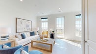 Located in the heart of historic Charleston, SC, this sophisticated three-story home blends coastal charm with modern elegance. The ground level features a spacious garage with polished concrete floors, a utility room, and convenient access to the upper floors via multiple staircases.

The main living floor is the heart of the home, showcasing a beautifully open-concept kitchen, dining, and living area bathed in natural light. The chef's kitchen is a standout, featuring a large center island with a striking blue base, white quartz countertops, custom gray cabinetry with brass hardware, a professional-grade range, and elegant glass pendant lighting. The adjacent dining area flows seamlessly into a bright, airy living room with French doors opening to a private balcony offering sweeping water views.

Wide-plank hardwood floors run throughout, complementing the clean white walls and crown molding that define each space. The upper floor hosts three well-appointed bedrooms, including a generous primary suite, alongside three full bathrooms. Abundant closet space — with eight closets total — adds exceptional practicality. A dedicated laundry room adds further convenience. The home's coastal-modern palette, abundant natural light, and panoramic views create a refined yet relaxed living experience.