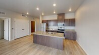 Located at 1408 21st Ave NW in Austin, Minnesota, this single-floor residence offers a clean, modern design with a bright and welcoming atmosphere throughout. The open-concept layout connects the living area and kitchen seamlessly, both finished with light wood-tone luxury vinyl plank flooring that enhances the sense of space and warmth.

The kitchen is a standout feature, equipped with rich dark espresso cabinetry, granite countertops, and a full suite of stainless steel appliances including a refrigerator, electric range, and built-in microwave. A central island with an undermount sink and matching granite surface provides additional prep space and serves as a natural gathering point.

The living area is generously sized and filled with natural light from a large window and sliding glass door that opens to a private outdoor balcony, offering a seamless indoor-outdoor connection. A wall-mounted HVAC unit ensures year-round comfort.

The bedroom includes plush carpet flooring and a dedicated closet with built-in wire shelving, providing practical storage. The bathroom is thoughtfully appointed with a tub-shower combination, wood-tone flooring, a granite-topped vanity with dark cabinetry, and chrome fixtures. Panel-style doors with brushed hardware are featured throughout, contributing to the unit's cohesive, contemporary aesthetic.