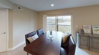 This single-floor residence features two bedrooms and two bathrooms within a thoughtfully arranged floor plan. The kitchen is equipped with rich dark-wood cabinetry, dark granite-style countertops, and a full suite of stainless steel appliances, including a range, built-in microwave, and refrigerator. Track lighting illuminates the space, which is complemented by warm hardwood-style flooring throughout.

The living and dining areas feature plush carpeting, recessed lighting, and large windows with vertical blinds that allow natural light to fill the rooms. The dining area includes a sliding glass door opening to a private balcony with outdoor views.

Both bedrooms are carpeted and finished with neutral tones. The primary bedroom is generously sized with direct access to its own bathroom, while the second bedroom includes a built-in closet with shelving. Each bathroom is finished with tile flooring. The first bathroom features a white vanity with ample counter space and a shower-tub combination, while the second includes a glass-enclosed shower and chrome fixtures throughout.