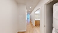 Located on the seventh floor at 1100 Boylston Ave in Seattle's Capitol Hill neighborhood, this one-bedroom, one-bathroom unit offers a thoughtfully designed layout with modern finishes throughout. Light hardwood flooring runs continuously across the entire space, creating a warm and cohesive feel from room to room.

The galley-style kitchen is outfitted with wood-toned cabinetry, white quartz countertops, a subway tile backsplash, stainless steel appliances, and recessed lighting — a clean and functional design ideal for everyday use. A sliding barn-style door adds a contemporary touch at the kitchen entrance.

The living area is bright and open, featuring large sliding glass doors that lead to a private balcony with city views, allowing natural light to fill the space. A wall-mounted mini-split unit ensures comfortable climate control year-round.

The bedroom is a well-proportioned retreat with its own balcony access, a high clerestory window for added natural light, and a dedicated walk-in closet with wrap-around hanging rods providing generous storage.

The bathroom features a long wood-grain vanity with a white countertop, a large mirror, and a tiled shower area. The hallway connecting each room is lined with recessed lighting and reinforces the unit's clean, modern aesthetic.