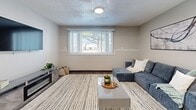 Located at 4200 Park Ave in Des Moines, Iowa, this well-appointed single-floor residence offers one bedroom, three bathrooms, a dedicated office, and a combined dining room and kitchen — all thoughtfully arranged for comfortable, functional living. The living room features wood-look flooring, a large window with vertical blinds that invite natural light and outdoor views, and a built-in display shelf that adds a decorative touch. The adjacent dining area is highlighted by a striking sputnik chandelier overhead and light hardwood-style flooring, creating an inviting space for meals and gatherings. The kitchen is outfitted with gray shaker-style cabinetry, matte black hardware, a single-basin sink with a matching black faucet, and sleek marble-look countertops that lend a modern, polished aesthetic. The spacious primary bedroom features plush carpet, a ceiling fan with light fixture, and a double-door closet. A dedicated office with carpeted floors and a natural-light window provides an ideal work-from-home environment. Three bathrooms serve the residence, including one with a full soaking tub and shower combination. Neutral tones, consistent finishes, and clean lines create a cohesive and contemporary ambiance throughout the entire space.