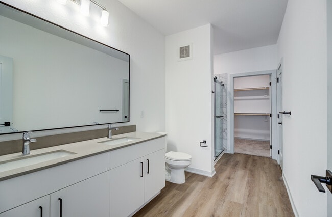 Un tocador doble con dos lavabos, un gran espejo con marco negro y una ducha a ras de suelo conectan directamente con el vestidor para ofrecer una experiencia de suite impecable, al estilo de un hotel. - Garrett Forum
