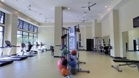 Located at 211 River Landing Dr. on Daniel Island, SC, this fitness center offers a thoughtfully designed, single-floor workout facility suited for a wide range of exercise routines. The space features soaring ceilings with recessed lighting and multiple ceiling fans that keep the environment comfortable during workouts. Large windows allow natural light to fill the room, creating an open and energizing atmosphere with views of the surrounding greenery.

The facility is well-equipped with a variety of fitness equipment to accommodate diverse training needs. Cardio enthusiasts will find a row of treadmills and other aerobic machines positioned along one side of the room. A multi-station cable machine anchors the central area, complemented by a collection of resistance bands, medicine balls, and stability balls organized on a dedicated rack. On the opposite side, a cable weight stack and free weight rack offer additional strength training options.

The flooring is finished in a clean, light-toned surface appropriate for high-traffic gym use, and the neutral wall tones contribute to the bright, airy feel of the space. Structural columns are integrated throughout without impeding the open layout. The overall design prioritizes functionality and accessibility, making this fitness center a practical and inviting resource for residents and visitors of the Daniel Island community.