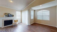 This single-floor residence offers a thoughtfully designed layout with a warm, neutral color palette throughout. The spacious living room is a standout feature, boasting vaulted ceilings, rich hardwood-style flooring, a classic fireplace with a white mantle, and multiple windows dressed with horizontal blinds that invite an abundance of natural light. Sliding glass doors provide convenient access to the outdoors. The kitchen is well-equipped with light wood cabinetry, gleaming granite countertops, a diamond-patterned tile backsplash, stainless steel appliances including a range and over-the-range microwave, and a double sink — all complemented by the same hardwood-style flooring. The bedrooms are carpeted for comfort, featuring crown molding, ample natural light, and walk-in closets with built-in shelving. One bedroom highlights a charming bay window arrangement, flooding the space with light. The bathroom is finished with granite countertops, light wood vanity cabinetry, hardwood-style flooring, and a tub-shower combination framed by classic white subway tile. Overall, the space presents a clean, move-in ready ambiance with consistent, quality finishes throughout.