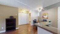 This single-story residence offers a thoughtfully organized layout that connects living, dining, and kitchen areas in a cohesive open arrangement. The living room features warm wood-look flooring, a corner fireplace, and a sliding glass door that allows natural light to fill the space. A ceiling fan overhead and neutral-toned walls contribute to a comfortable, relaxed ambiance throughout the common areas.

The kitchen is efficiently designed with white cabinetry, a double stainless steel sink, laminate countertops, and a white electric range beneath an overhead exhaust hood. A window with blinds brings in additional natural light. Adjacent to the kitchen, the dining area accommodates a round glass-top table with upholstered seating and is accented by a ceiling fan and decorative wall art.

A large double-door closet in the main living area provides generous storage. The two bedrooms are carpeted and well-sized, each offering ample space for furnishings. One bedroom features a teal accent wall with a window, while the other offers a serene, neutral palette.

The full bathroom includes a vanity with white cabinetry and laminate countertop, a large mirror, and a tub-shower combination with a decorative curtain.