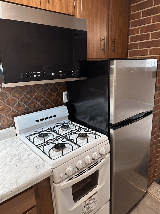 Cocina americana equipada con nevera, cocina de gas de cuatro fuegos y microondas con campana extractora. - 834 S Walnut St