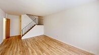 Located at 8875 Ridge Ave in the Roxborough neighborhood of Philadelphia, this two-story home offers two bedrooms and two bathrooms across two thoughtfully laid-out floors. The main level features a bright living room with warm hardwood-style flooring and an elegant staircase with decorative wrought-iron railings. Adjacent to the living area, the galley-style kitchen is well-equipped with stainless steel appliances — including a refrigerator, range, and dishwasher — complemented by warm wood cabinetry, granite-style countertops, and tile flooring. A ceiling fan and window at the far end of the kitchen add natural light and airflow. The upper level hosts two carpeted bedrooms, each featuring natural light from windows. The spacious primary bedroom includes a built-in closet with bifold doors, while the second bedroom offers comfortable proportions and easy hallway access. Both bathrooms are clean and functional; one features classic black-and-white tile work, a tub-shower combination, a mirrored medicine cabinet, and a pedestal-style vanity. A dedicated closet and hallway complete the upper floor, providing practical storage solutions throughout.