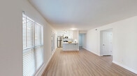 Located at 1200 Trillium Cir in Raleigh, NC, this well-appointed 2-bedroom, 2-bathroom single-floor home offers a thoughtfully designed layout with modern finishes throughout. Light-toned hardwood-style flooring flows seamlessly across the entire space, complemented by crisp white walls and clean trim that create a bright, welcoming atmosphere.

The open-concept living and dining area is generously proportioned, bathed in natural light from multiple windows dressed with white horizontal blinds. This space connects directly to the kitchen, making it ideal for everyday living and entertaining. The kitchen is a standout feature, showcasing white shaker-style cabinetry, granite countertops with subtle grey veining, stainless steel appliances including a refrigerator, range, microwave, and dishwasher, a double undermount sink, pendant lighting, and a built-in pantry with louvered bifold doors.

Both bedrooms offer comfortable, well-sized layouts with hardwood-style flooring and ample closet space — the primary bedroom includes multiple closets. The two bathrooms are finished with granite-topped vanities and tile flooring. One bathroom features a walk-in glass-door shower with large-format tile surround and a built-in niche. Additional conveniences include a dedicated laundry area, utility room, entrance foyer, and hallway connecting all spaces efficiently.