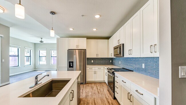 Unidad de apartamento de lujo Imperial Crossing que muestra una cocina moderna con electrodomésticos de acero inoxidable y gabinetes blancos. - Imperial Crossing Luxury Apartment Homes