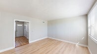 Located at 490 Ellis St in New Britain, CT, this two-story residence offers a practical and well-organized layout across two floors. The main level features a bright living room with light luxury vinyl plank flooring, vertical shiplap-style wall paneling, and a large front-facing window that invites natural light. Adjacent to the living room is a functional kitchen equipped with white cabinetry, granite-style countertops, a gas range, and a full-size refrigerator, complemented by a ceiling fan and a door providing direct exterior access. A pantry and utility room add convenient storage on this floor.

The upper level houses both bedrooms, connected by a hallway and staircase. The bedrooms feature warm-toned hardwood flooring and are serviced by three closets for ample storage. The full bathroom is tiled floor-to-ceiling in neutral beige, with a tub/shower combination, a pedestal-style vanity, a round mirror, and a small window for ventilation. The space also includes a second staircase, adding to the functional flow between floors.

Throughout, the interior presents a clean, neutral palette of soft grays and whites, creating a cohesive and move-in-ready environment suitable for a variety of living arrangements.