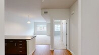 Located at 331 Justison Street in Wilmington, Delaware, this one-bedroom, one-bathroom residence offers a well-organized layout across a single floor. The open-concept kitchen and living area serves as the heart of the home, featuring rich dark-brown cabinetry, stainless steel appliances including a refrigerator, electric range, and microwave, along with a peninsula countertop finished in a sleek concrete-tone surface that provides additional workspace and a natural divide between the kitchen and living area. Hardwood-style flooring anchors the kitchen, while the living space transitions to plush neutral carpeting that extends throughout the remainder of the unit. The bedroom is a comfortable, well-proportioned retreat finished with the same soft carpeting and bright white walls. A window offers views of the surrounding Wilmington cityscape and green tree canopy, filling the room with natural light. The full bathroom is clean and functional, featuring a tiled tub-and-shower combination with a curved curtain rod and tile flooring. A dedicated utility room accommodates in-unit laundry, adding everyday convenience. Throughout the residence, crisp white walls, consistent flooring materials, and a neutral palette create a cohesive, move-in-ready environment.