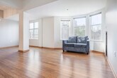 This well-appointed 3-bedroom, 2-bathroom single-floor residence offers a thoughtfully designed layout that balances comfort and functionality. The open living area is a highlight of the home, anchored by a striking bay window configuration that floods the space with natural light and offers expansive views of the surrounding urban landscape and tree canopy. Warm hardwood flooring extends throughout the main living areas, complementing the bright, white walls and creating an inviting ambiance.

The galley-style kitchen is efficiently designed with honey-toned wood cabinetry, quartz-style countertops, tile backsplash, and stainless steel appliances, including a refrigerator and electric range. A hallway with an elegant orb chandelier connects the main living spaces to the private quarters.

The three bedrooms are carpeted and well-lit, each featuring windows with city and nature views. The primary bedroom includes a built-in closet, while additional bedrooms offer similar closet storage. Two full bathrooms serve the unit — one featuring tile flooring and a tub/shower combo, the other with dark upper cabinetry, a granite-style vanity, and a shower/tub. The overall design is clean, neutral, and move-in ready.
