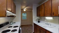 Located at 714 Riverside Drive in Salisbury, Maryland, this single-floor residence offers a practical and comfortable living environment. The kitchen is a standout feature, thoughtfully designed with rich, warm-toned wood cabinetry that provides generous storage above and below the countertops. A clean, white sink sits beneath the cabinetry, complemented by a white electric range, making the space both functional and easy to maintain. The kitchen's layout follows a galley-style configuration, allowing for efficient use of space while maintaining an open sightline into the adjacent area. A ceiling fan overhead ensures comfortable airflow throughout. Natural light filters in through a window that frames a view of surrounding greenery, bringing a touch of the outdoors inside and adding brightness to the interior. The flooring transitions from the kitchen into a carpeted area, adding warmth underfoot in the connected living space. The overall ambiance of the home is cozy and practical, with a neutral color palette that provides a welcoming, move-in-ready feel. The residence is ideally positioned in Salisbury, a city known for its riverside character and community-oriented neighborhoods.