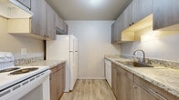 This single-floor unit in Royal Oak, Michigan, offers a thoughtfully organized layout that maximizes its footprint. The galley-style kitchen is a functional highlight, featuring wood-toned cabinetry with brushed nickel hardware, light granite-style countertops, and wood-look luxury vinyl plank flooring. White appliances, including a refrigerator, electric range, and dishwasher, are neatly integrated along both walls, providing ample prep and storage space.

The living area is generously proportioned, with soft, neutral-toned carpeting and baseboard heating that runs along the perimeter walls, ensuring year-round comfort. The open, clean lines of the space offer flexibility for a variety of furniture arrangements. The bedroom is a comfortable, private retreat, also finished with plush carpeting and baseboard heating, and receives natural light through a window fitted with blinds.

The bathroom is a refined space, featuring large-format wood-look floor and wall tiles, a walk-in shower with sliding glass doors, a vanity with matching cabinetry, and a light stone-style countertop. The neutral palette throughout the unit creates a cohesive, understated aesthetic well-suited to a range of interior styles.
