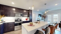 This thoughtfully designed single-floor residence offers 3 bedrooms and 3 bathrooms, combining modern aesthetics with functional living. The open-concept kitchen and living area serves as the heart of the home, featuring a sleek kitchen with rich dark cabinetry, white quartz countertops, stainless steel appliances, and a large center island with an undermount sink and pendant lighting — ideal for both cooking and casual dining. The adjacent living room is bright and welcoming, with light wood-style flooring, a ceiling fan, and French doors that open to a private balcony, allowing natural light to fill the space. The primary bedroom is generously sized, offering a ceiling fan, a large window with natural light, and ample room for a seating area. The additional bedrooms are equally well-lit and comfortable. All three bathrooms maintain a clean, modern design with dark cabinetry, white quartz vanities, brushed nickel fixtures, and wood-style flooring. One bathroom features a full tub-shower combination with tiled surround. Throughout the home, light wood-style flooring, recessed lighting, and a neutral color palette create a cohesive, contemporary ambiance.