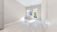 Located at 2555 Riva Rd in Annapolis, MD, this thoughtfully designed one-bedroom, two-bathroom unit offers a clean, contemporary aesthetic throughout its single-floor layout. Light wood-look flooring flows seamlessly across all rooms, creating a bright and cohesive interior.

The kitchen is a standout feature, showcasing gray shaker-style cabinetry, a herringbone-patterned tile backsplash, stainless steel appliances including a French door refrigerator, a gas range, built-in microwave, and dishwasher. A freestanding island provides additional prep space and a casual dining option.

The bedroom is well-proportioned and filled with natural light from large windows and a glass balcony door that opens to a private outdoor space with greenery views. The room also features a ceiling fan and access to a walk-in closet.

Both bathrooms maintain the same modern palette, with gray vanity cabinetry, white countertops, and gold-toned hardware accents. The primary bathroom includes a glass-enclosed marble-tiled shower, adding an elevated, spa-like touch.

Throughout the unit, neutral warm-beige walls, recessed lighting, and clean white trim contribute to an airy, move-in-ready ambiance well-suited for comfortable everyday living.