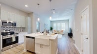 Located at 14355 North Main Street in Jacksonville, FL, this well-appointed 2-bedroom, 3-bathroom single-floor residence offers a thoughtfully designed open-concept layout with clean, modern finishes throughout. Light wood-tone flooring flows seamlessly across the living spaces, complemented by soft neutral wall tones that create a bright and welcoming ambiance.

The kitchen serves as the heart of the home, featuring white cabinetry, a decorative patterned tile backsplash, stainless steel appliances, and a central island with a farmhouse-style sink and pendant lighting overhead — ideal for both casual dining and entertaining. The kitchen opens directly into the dining and living areas, where large windows invite abundant natural light.

The spacious primary bedroom includes a walk-in closet outfitted with wire shelving, and an en-suite bathroom with dual granite-top vanities and a glass-enclosed shower. A second well-sized bedroom also benefits from natural light through large windows. The additional bathrooms are finished with granite countertops, white cabinetry, and tiled shower-tub combinations. A dedicated laundry room and two closets add to the home's practical storage options, rounding out a functional and attractive living space.