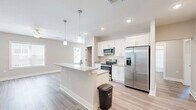 Located at 124 Center Church Rd in Sanford, NC, this single-story 2-bedroom, 2-bathroom home offers a thoughtfully designed floor plan with a clean, modern aesthetic throughout. The open-concept kitchen and living area serves as the heart of the home, featuring white shaker-style cabinetry, granite countertops, a subway tile backsplash, stainless steel appliances including a French door refrigerator and electric range, and a central island with a double basin sink and pendant lighting above. Light wood-look flooring flows throughout the main living areas, lending a bright and cohesive feel. Large windows in the living area allow generous natural light and views of the surrounding greenery. Both bedrooms are carpeted and include ceiling fans, with the primary bedroom offering ample closet space. A secondary bedroom also benefits from natural light through a large window. The two bathrooms are finished with wood-look flooring and include walk-in shower stalls. A dedicated laundry room comes equipped with a washer and dryer unit and overhead shelving for storage. Additional storage is provided through multiple closets and a pantry. The home also includes a utility room, completing a practical and comfortable single-floor living arrangement.