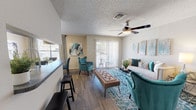 Located at 5622 Evers Rd in San Antonio, Texas, this single-floor unit offers a cohesive and thoughtfully designed living space with a consistent style carried throughout each room. The open-concept living and dining area serves as the heart of the home, featuring wood-look flooring, a textured ceiling, and a ceiling fan with integrated lighting. The living room provides ample space for comfortable seating arrangements and is brightened by natural light flowing in through sliding glass doors that lead to a balcony. A pass-through window connects the living and dining area to the kitchen, enhancing the open feel of the space. The galley-style kitchen is outfitted with dark cabinetry, granite-style countertops, subway tile backsplash, a double-basin sink, and black appliances, offering both functionality and style in a well-organized layout. The bedroom is a calm retreat, featuring wood-look flooring, a ceiling fan, natural light from a window with drape panels, and ample room for a dresser and nightstand. The bathroom includes a full tub and shower combination with white tile surround and clean, neutral finishes. Throughout the unit, a cohesive neutral color palette is accented with warm wood tones, creating a welcoming and modern atmosphere.