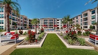 Located at 15915 Kingfield Dr in Houston, TX, this outdoor amenity courtyard is designed to deliver a resort-style living experience. The centerpiece is a generously sized swimming pool with clear blue water, surrounded by a broad, smooth concrete sun deck outfitted with rows of white lounge chairs and bold red market umbrellas, providing ample space for relaxation under the Texas sun. Tropical palm trees and vibrant flowering plants are thoughtfully arranged throughout the grounds, creating a lush, resort-inspired atmosphere. A dedicated fire pit lounge area features stylish outdoor seating arranged around a modern square fire table, ideal for evening gatherings. An outdoor kitchen and entertainment pavilion, partially covered and open to the courtyard, is equipped with seating, a mounted television, and grill stations, making it well suited for social events. Manicured turf pathways and curved concrete walkways connect the various amenity zones, lending a cohesive and polished feel to the overall layout. The multi-story residential buildings surrounding the courtyard feature a contemporary design with brick and stone accents, large windows, and private balconies, all oriented to overlook this vibrant outdoor community space.