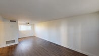 Located at 1220 E Medlock Dr in Phoenix, Arizona, this single-floor unit offers a clean, modern aesthetic with thoughtful updates throughout. The open living area is a standout feature, showcasing rich dark hardwood-style flooring, crisp white walls, and vertical blinds that allow natural light to filter in. A ceiling fan adds both style and comfort to the space. A sliding glass door leads to an outdoor area, bringing in additional natural light and a connection to the exterior.

The kitchen is efficiently designed with white cabinetry extending to the ceiling for ample storage, stainless steel appliances including a refrigerator, range, and microwave, all set beneath recessed lighting and complemented by light wood-tone flooring.

The bedroom continues the bright and airy theme with plush neutral carpeting, a ceiling fan with light fixture, and a window dressed with vertical blinds.

The bathroom is a refined retreat, featuring striking marble-look tile that lines the tub and shower surround from floor to ceiling. A glass enclosure, brushed nickel fixtures, a wall-mounted vanity with a modern basin sink, and wood-style flooring complete the polished look. A small window provides natural ventilation, adding to the bathroom's fresh and clean ambiance.
