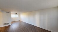 Located at 1220 E Medlock Dr in Phoenix, Arizona, this single-floor unit offers a clean, modern aesthetic with thoughtful updates throughout. The open living area is a standout feature, showcasing rich dark hardwood-style flooring, crisp white walls, and vertical blinds that allow natural light to filter in. A ceiling fan adds both style and comfort to the space. A sliding glass door leads to an outdoor area, bringing in additional natural light and a connection to the exterior.

The kitchen is efficiently designed with white cabinetry extending to the ceiling for ample storage, stainless steel appliances including a refrigerator, range, and microwave, all set beneath recessed lighting and complemented by light wood-tone flooring.

The bedroom continues the bright and airy theme with plush neutral carpeting, a ceiling fan with light fixture, and a window dressed with vertical blinds.

The bathroom is a refined retreat, featuring striking marble-look tile that lines the tub and shower surround from floor to ceiling. A glass enclosure, brushed nickel fixtures, a wall-mounted vanity with a modern basin sink, and wood-style flooring complete the polished look. A small window provides natural ventilation, adding to the bathroom's fresh and clean ambiance.