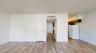 Located on E Fort Lowell Rd in Tucson, Arizona, this single-story, 2-bedroom, 1-bathroom unit offers a straightforward and functional layout. The living room serves as the central gathering space, featuring wood-look plank flooring, white cinder block walls, a textured ceiling, and a ceiling fan. Two windows flank the front entry door, allowing natural light to fill the room and offering views of surrounding greenery.

The kitchen sits adjacent to the living area in an open-concept arrangement and is equipped with dark brown cabinetry, light countertops, a stainless steel sink, an electric range, and a full-size refrigerator. Wood-look flooring continues through this space, complementing the cabinetry tones.

Both bedrooms feature soft gray carpeting, white cinder block walls, and closet storage. The primary bedroom includes a spacious walk-in closet with a full-length hanging rod. Natural light enters through windows fitted with vertical blinds or curtains, lending a bright, airy feel to each room.

The bathroom includes a single-vanity with a warm-toned countertop, dark wood cabinetry, a combined tub and shower, and a window providing natural ventilation and light. Wood-look flooring ties the space together cohesively throughout.