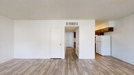 Located on E Fort Lowell Rd in Tucson, Arizona, this single-story, 2-bedroom, 1-bathroom unit offers a straightforward and functional layout. The living room serves as the central gathering space, featuring wood-look plank flooring, white cinder block walls, a textured ceiling, and a ceiling fan. Two windows flank the front entry door, allowing natural light to fill the room and offering views of surrounding greenery.

The kitchen sits adjacent to the living area in an open-concept arrangement and is equipped with dark brown cabinetry, light countertops, a stainless steel sink, an electric range, and a full-size refrigerator. Wood-look flooring continues through this space, complementing the cabinetry tones.

Both bedrooms feature soft gray carpeting, white cinder block walls, and closet storage. The primary bedroom includes a spacious walk-in closet with a full-length hanging rod. Natural light enters through windows fitted with vertical blinds or curtains, lending a bright, airy feel to each room.

The bathroom includes a single-vanity with a warm-toned countertop, dark wood cabinetry, a combined tub and shower, and a window providing natural ventilation and light. Wood-look flooring ties the space together cohesively throughout.
