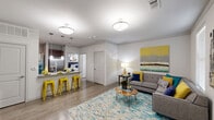 Located along West Lake Houston Parkway in Houston, TX, this 2-bedroom, 2-bathroom residence offers a thoughtfully designed single-floor layout that balances comfort and functionality. The open-concept living and kitchen area serves as the heart of the home, featuring wood-style flooring that flows seamlessly throughout. The kitchen is outfitted with rich dark cabinetry, granite countertops, stainless steel appliances including a refrigerator, range, and microwave, and a breakfast bar with pendant lighting — ideal for casual dining. The living room is generously proportioned, bathed in natural light through large windows with blinds, and finished with clean neutral walls. Both bedrooms are carpeted and include ceiling fans, ample closet space, and large windows. The spacious primary bedroom comfortably accommodates a queen or king-size bed. Each of the two bathrooms features granite-topped vanities with dark wood cabinetry and tub-shower combinations with tile surrounds. A dedicated in-unit laundry room adds everyday convenience. The overall design is modern and cohesive, with consistent finishes throughout that create a polished, move-in-ready living environment.