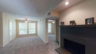 Located at The Village, this single-floor residence offers a well-organized layout designed for comfortable everyday living. The main living area is a generously sized, carpeted space anchored by a striking dark brick fireplace with a wood mantle, serving as a central focal point. Ceiling fans are installed throughout, and large windows invite abundant natural light while offering pleasant views of surrounding greenery. An open entryway connects the living space to an additional carpeted room, ideal for use as a dining or flex space, also equipped with a ceiling fan and windows.

The kitchen is efficiently designed in a U-shaped layout, featuring warm wood cabinetry, laminate countertops, tile flooring, a black range with overhead ventilation, and a double stainless steel sink. Ample cabinet storage lines the walls, providing practical functionality.

The bedrooms are carpeted and well-proportioned, each with large windows that bring in natural light and views of the tree-lined exterior. Ceiling fans are present in several rooms, adding comfort and airflow.

The bathrooms feature warm wood vanity cabinetry with laminate countertops, large mirrors, and tile flooring. Both bathrooms are functional and neatly appointed, with shower-tub combinations and well-lit vanity areas.