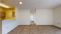 This single-floor, 3-bedroom, 2-bathroom residence offers a practical and comfortable layout designed for everyday living. The living room greets you at the entrance with warm, neutral-toned carpet, a textured ceiling, and a sliding glass door fitted with vertical blinds that allows natural light to fill the space. Adjacent to the living area, the galley-style kitchen is equipped with stainless steel appliances — including a refrigerator, electric range, and dishwasher — complemented by gray cabinetry, white countertops, and wood-look vinyl flooring that adds a clean, contemporary feel. A central hallway connects the main living areas to the bedrooms and bathrooms, providing an efficient flow throughout the home. The primary bedroom is generously sized, featuring plush carpet and a window with outdoor views. The two additional bedrooms are similarly appointed with soft carpet and ample natural light. Both bathrooms feature wood-look vinyl flooring, gray vanity cabinetry, white countertops, and a tiled tub-shower combination. Two closets provide convenient storage solutions. The overall design is light, neutral, and move-in ready, creating a clean and welcoming atmosphere throughout.