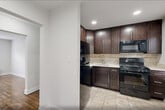 Located at 1127 John F. Kennedy Blvd in Bayonne, NJ, this well-appointed one-bedroom, one-bathroom unit offers a thoughtfully designed single-floor layout. Rich, polished hardwood floors run throughout the living areas and bedroom, lending warmth and character to the space. The living room is bright and open, featuring recessed lighting, multiple windows that invite natural light, and a classic radiator for efficient heating. An entrance leads conveniently into the home, with four closets distributed throughout, providing generous storage. The kitchen is well-equipped with rich dark-stained wood cabinetry reaching to the ceiling, a stone tile backsplash, black appliances including a gas range, microwave, and refrigerator, and light ceramic tile flooring — all complemented by a window overlooking the outdoors. The bedroom is a comfortable and quiet retreat, fitted with a wall-unit air conditioner, radiator heat, and a window with natural views. The bathroom is clean and functional, featuring white subway tile surrounding a tub-shower combination with a sliding glass door, a white vanity with sink, and a frosted privacy window. Neutral gray walls throughout create a calm, cohesive aesthetic ideal for modern living.