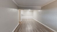 Located at 8128 Barclay St in Dallas, TX, this 2-bedroom, 1-bathroom unit offers a practical and well-appointed single-floor layout. Wood-look vinyl plank flooring runs consistently throughout the space, lending a clean, cohesive aesthetic to every room. The living room is a standout area, distinguished by painted white brick accent walls that add texture and character, along with crown molding that frames the textured ceiling. Natural light filters in through windows fitted with horizontal blinds, enhancing the overall brightness of the space. Both bedrooms are comfortably sized with neutral-toned walls and windows that offer exterior views, creating a calm and functional retreat. The primary bedroom provides a cozy yet practical footprint. The bathroom features white tile wainscoting, a single-sink vanity with a mirror and overhead lighting, and a full bathtub and shower combo, all finished in a clean, bright palette. The kitchen area, visible in the floorplan, is positioned toward the rear of the unit. Throughout the space, consistent neutral gray and beige tones, white trim, and wood-look flooring create a unified, move-in-ready interior well-suited for everyday living in Dallas.