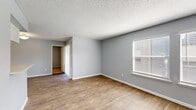 Located at 12801 Roydon Dr in Houston, TX, this single-floor, 2-bedroom, 2-bathroom unit offers a practical and comfortable layout across a thoughtfully designed floor plan. The living and dining areas are finished with warm wood-look flooring and cool gray walls, creating a clean, neutral aesthetic. A textured ceiling runs throughout the common areas, adding subtle character. The kitchen features white cabinetry, a gray subway tile backsplash, black appliances including a refrigerator and range, a built-in microwave, and a peninsula island with a white countertop that opens toward the dining and living spaces, ideal for casual interaction. Both bedrooms are carpeted and equipped with ceiling fans, offering a cozy retreat. The primary bedroom is generously sized and includes access to a closet, while both rooms feature window blinds that allow for natural light control. The two bathrooms are finished with white vanities, quartz-style countertops, framed mirrors, and wood-look tile flooring; one includes a walk-in shower and the other a full soaking tub. A private patio with a slatted wood and metal railing provides an outdoor retreat with neighborhood views. Two closets and dual hallways contribute additional storage and ease of circulation throughout the home.