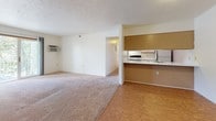 This single-floor, 2-bedroom, 1-bathroom residence offers a practical and well-organized layout designed for comfortable everyday living. The open living area features a combination of wood-look flooring and plush carpeting, creating distinct zones for relaxing and dining. A wall-mounted air conditioning unit provides climate control, while a baseboard heating system runs throughout the home. The galley-style kitchen is efficiently designed with ample white cabinetry trimmed in warm wood tones, white appliances including a range and refrigerator, a double sink, and wood-look flooring. A pass-through counter connects the kitchen to the living area, enhancing the open feel. The primary bedroom is generously sized, featuring two closets for abundant storage, a large window framing views of mature trees, and baseboard heating. The second bedroom is bright and inviting, with a sliding window that allows natural light and outdoor views to fill the carpeted space. A ceiling fan adds comfort to one of the bedrooms. The full bathroom includes a tub-shower combination, a vanity, tile flooring, and baseboard heating. The entry area features wood-look flooring and a closet for added convenience. Throughout the home, neutral tones and clean finishes create a calm, move-in-ready ambiance.