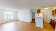 This single-floor residence offers two bedrooms and two full bathrooms within a well-organized layout. Light wood flooring runs consistently throughout the living areas and bedrooms, creating a cohesive and clean aesthetic. Textured ceilings are present throughout the unit.

The open living and dining area is bright and spacious, benefiting from natural light provided by multiple windows with blinds. A glass-paned door in the living area adds an additional source of natural light. The layout flows naturally toward the kitchen, which is separated by a half-wall peninsula. The galley-style kitchen features warm wood cabinetry, white appliances including a refrigerator and range, an undermount sink, and ample upper and lower cabinet storage. A pantry closet is located at the far end of the kitchen.

Both bedrooms are comfortably sized with white walls and wood flooring. At least one bedroom includes a closet with bifold doors and shelving. The two full bathrooms are similarly appointed, each featuring a wood-tone vanity with a white countertop and sink, a tub-shower combination with tile surround in neutral tones, and wood flooring.
