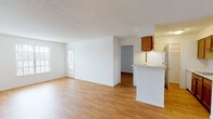 This single-floor residence offers two bedrooms and two full bathrooms within a well-organized layout. Light wood flooring runs consistently throughout the living areas and bedrooms, creating a cohesive and clean aesthetic. Textured ceilings are present throughout the unit.

The open living and dining area is bright and spacious, benefiting from natural light provided by multiple windows with blinds. A glass-paned door in the living area adds an additional source of natural light. The layout flows naturally toward the kitchen, which is separated by a half-wall peninsula. The galley-style kitchen features warm wood cabinetry, white appliances including a refrigerator and range, an undermount sink, and ample upper and lower cabinet storage. A pantry closet is located at the far end of the kitchen.

Both bedrooms are comfortably sized with white walls and wood flooring. At least one bedroom includes a closet with bifold doors and shelving. The two full bathrooms are similarly appointed, each featuring a wood-tone vanity with a white countertop and sink, a tub-shower combination with tile surround in neutral tones, and wood flooring.